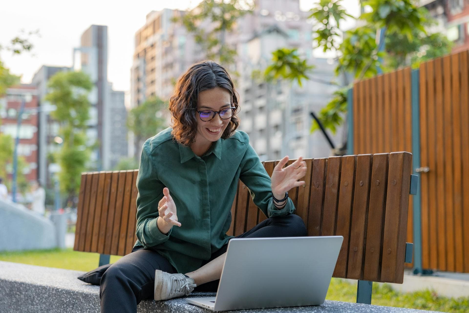 A job seeker working on a laptop on a park bench, gesturing while thinking out loud